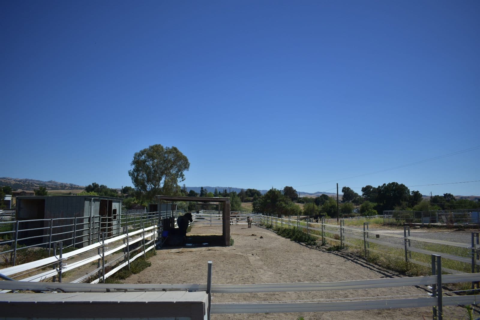 Wide view of the Crossroads property: turnouts, covered arena, and the surrounding hills