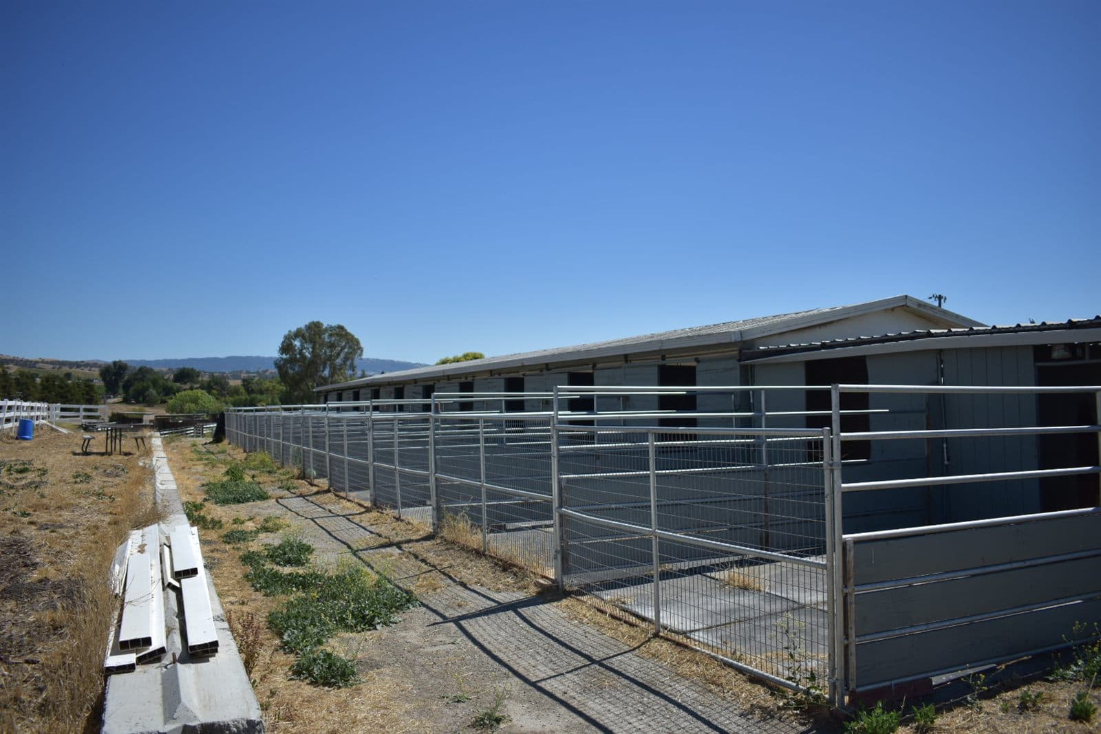 Row of covered stalls at the barn with the hills behind